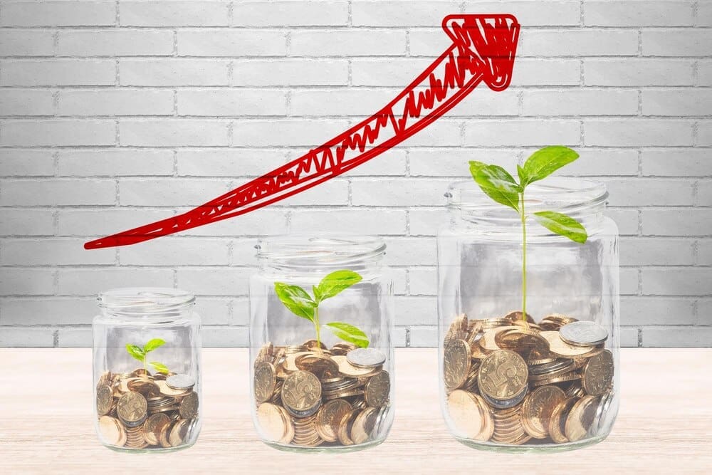 Glass jars filled with coins and small saplings are arranged in a line.