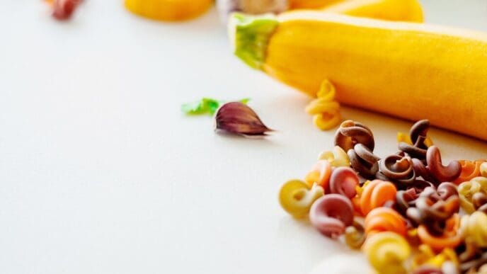 Close-up of ingredients for pasta, including tomatoes, spinach, and carrots, representing natural dyes.