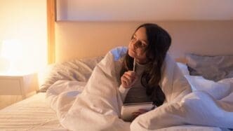 A small girl lies in bed, deep in thought, perhaps inspired by art or a hobby.