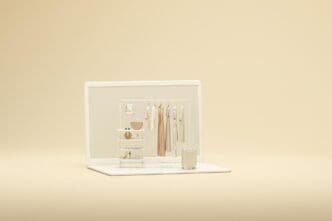 3D rendering of a laptop screen and clothing rack against a beige and white backdrop.