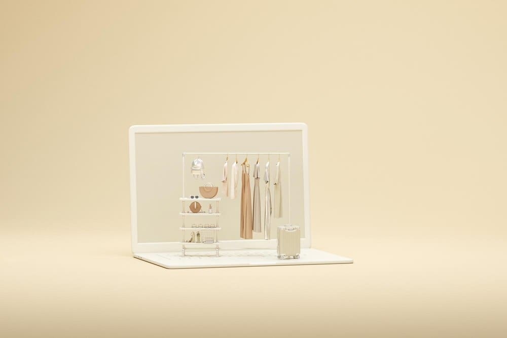 3D rendering of a laptop screen and clothing rack against a beige and white backdrop.