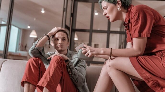 A green-haired woman looks surprised and disappointed while holding bank cards, likely indicating a lack of funds.