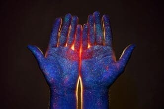 A person's hands are held up, with light shining through the fingers, evoking a sense of spirituality.