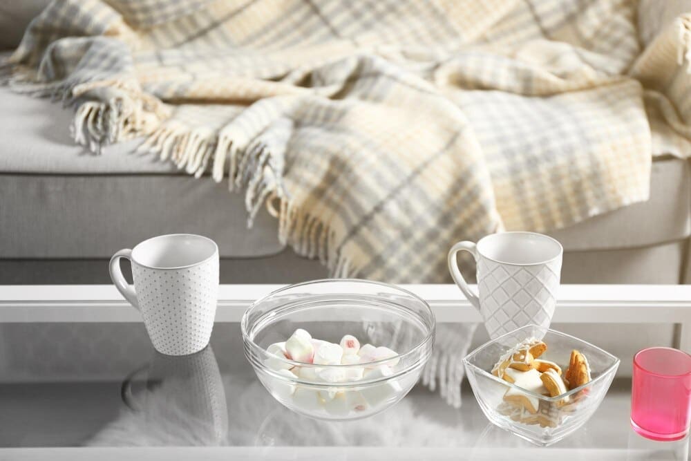 A low table in a living room displays sweets and two cups.