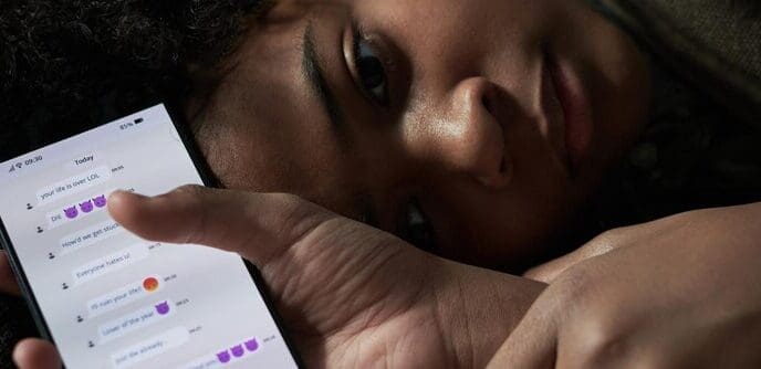 Person lying down, holding a smartphone and scrolling through messages.