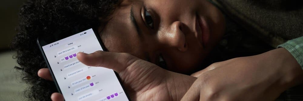 Person lying down, holding a smartphone and scrolling through messages.
