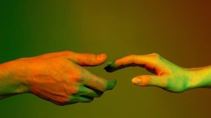 Hands of a man and woman reach toward each other, set against a red and green neon-lit background.