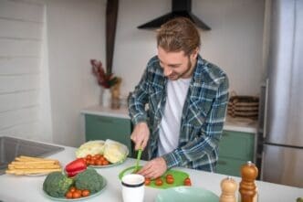 A man uses a knife to slice vegetables on a cutting board.