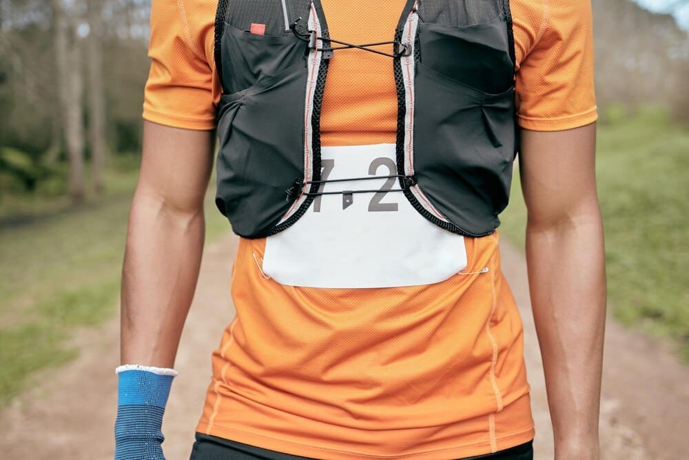 A male marathon runner sprints along a wooded path, likely during a race or outdoor fitness activity.