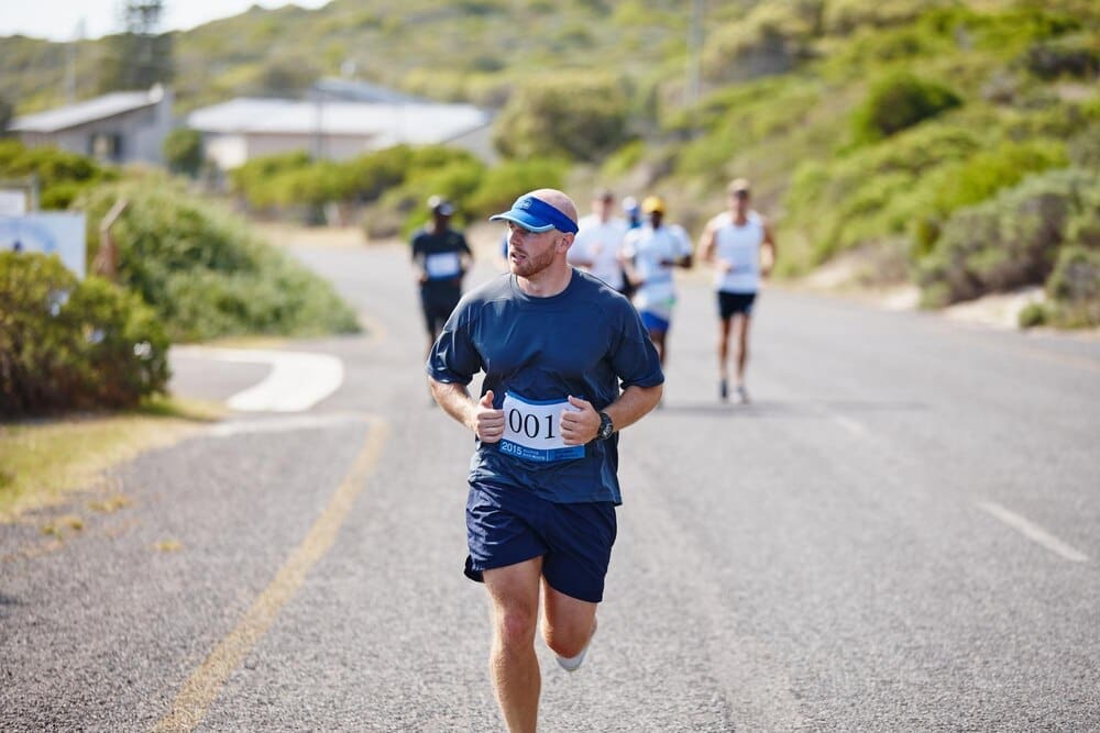A man participates in an outdoor triathlon, running a street race as part of the competition.