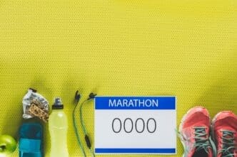 A flat lay shows various supplies for a marathon, including running shoes, water bottles, energy gels, and a race bib.