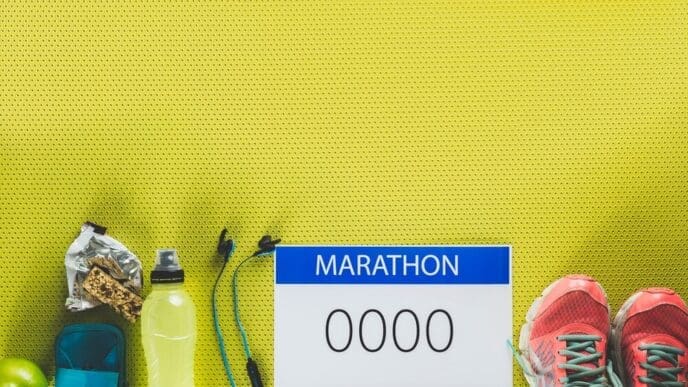 A flat lay shows various supplies for a marathon, including running shoes, water bottles, energy gels, and a race bib.