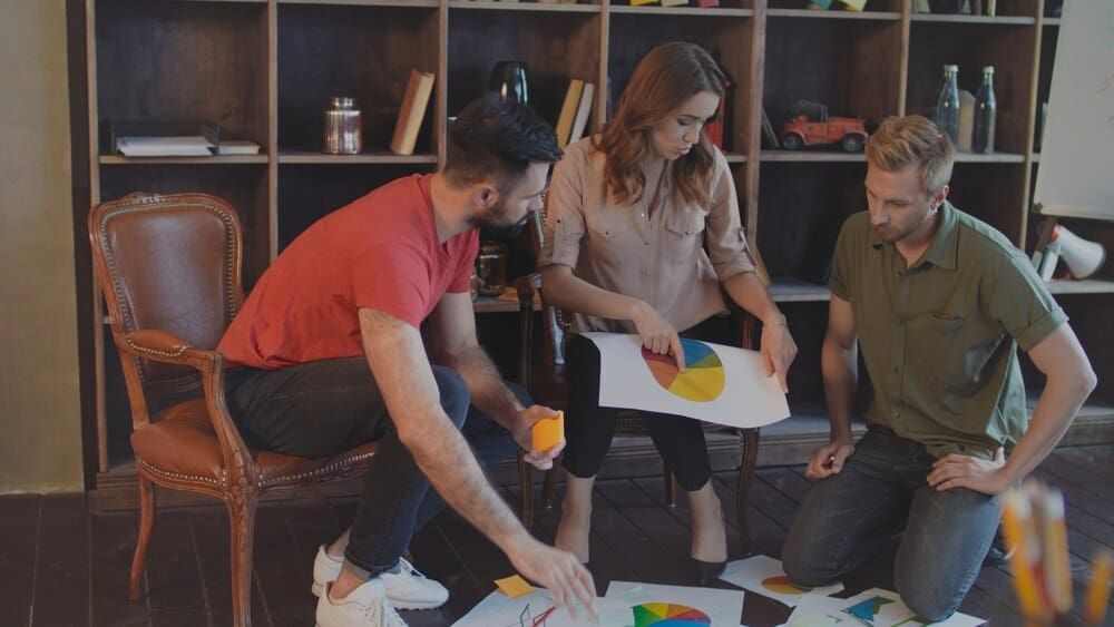A group of people in a creative business meeting analyze market statistics.