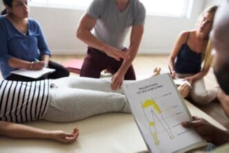 A group of people are participating in a massage therapy training class, practicing techniques on each other.