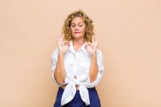 A middle-aged woman with a focused expression is meditating.