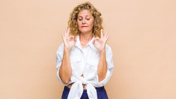 A middle-aged woman with a focused expression is meditating.