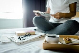 Man's midsection visible as he sits at a table and reads a book.
