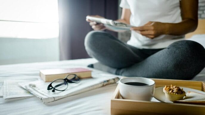 Man's midsection visible as he sits at a table and reads a book.