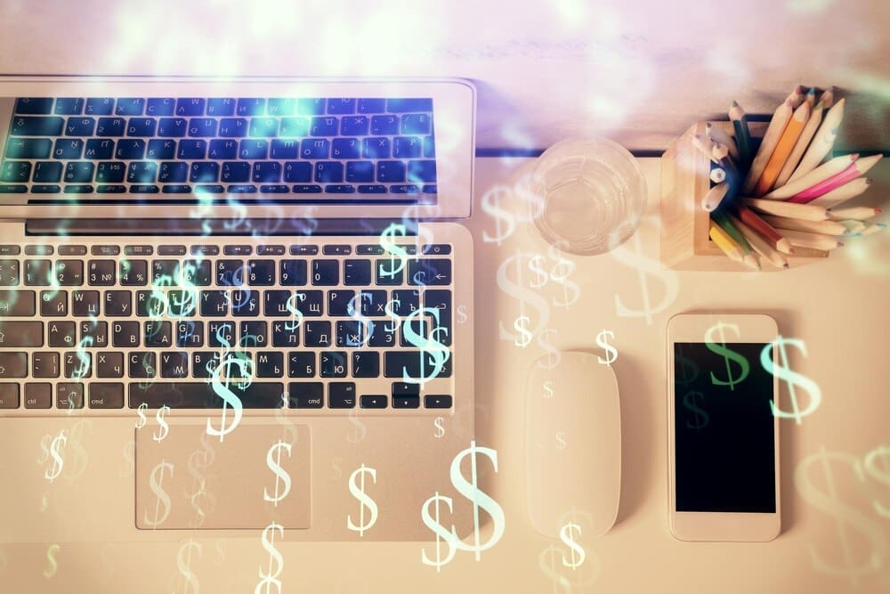 Overhead view of a desktop with a computer and a multi-exposure image of a forex graph overlayed.