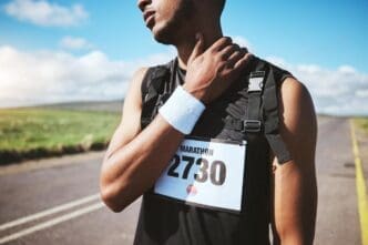 A marathon runner clutches their neck in pain, likely indicating a running-related injury or medical issue.