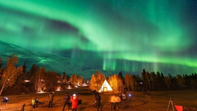 The night sky above Aurora Village in Yellowknife, Northwest Territories, Canada, is illuminated by the vibrant green and purple colors of the aurora borealis.