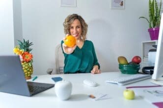 A nutritionist holds up an orange, representing healthy eating.