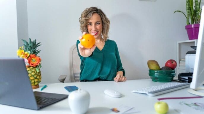 A nutritionist holds up an orange, representing healthy eating.