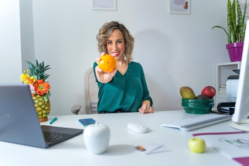 A nutritionist holds up an orange, representing healthy eating.
