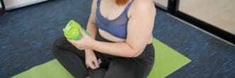 An overweight Asian woman in sportswear drinks a protein shake after exercising.