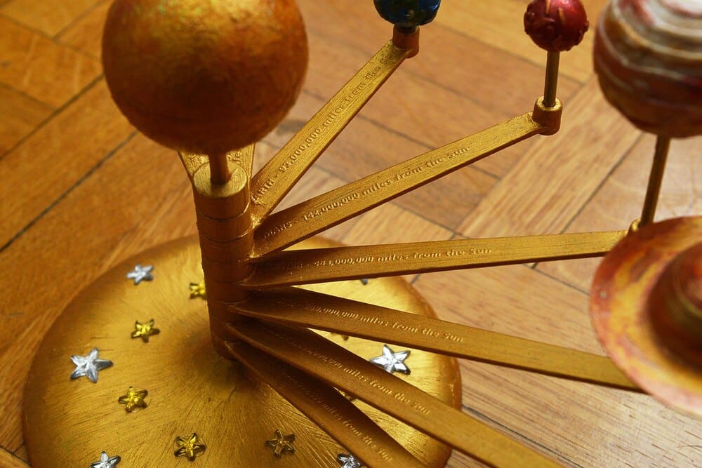 A mechanical orrery model depicts the relative positions and movements of the sun, Earth, and other planets.