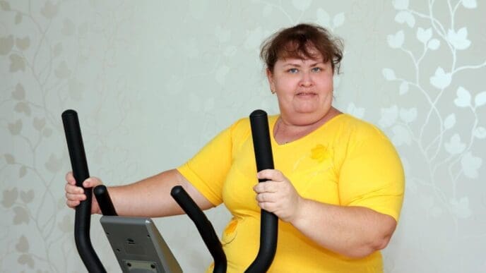 An overweight woman exercises on a stationary trainer.