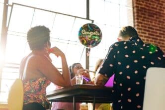 People of varying ages are gathered at a party, joyfully interacting with colorful balloons.
