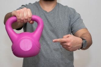 A person holds a pink dumbbell and points their finger.