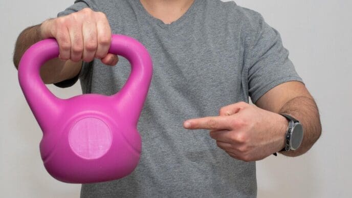 A person holds a pink dumbbell and points their finger.