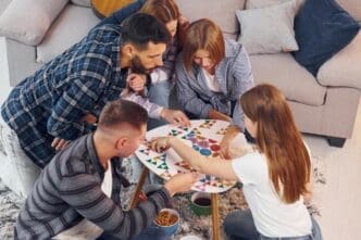 Friends gather indoors, laughing and working together to solve a puzzle.