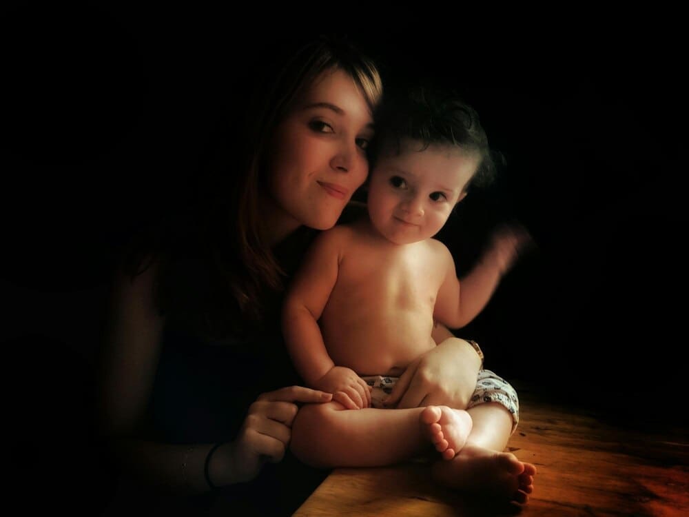 A smiling baby girl with a sweet expression is looking directly at the camera.