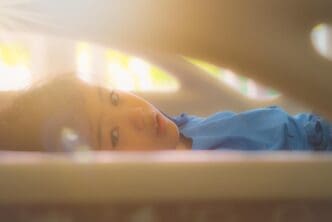 A young girl is lying down on a bed, likely resting or relaxing.