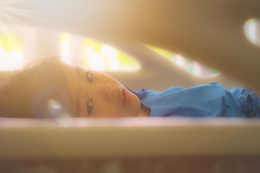 A young girl is lying down on a bed, likely resting or relaxing.