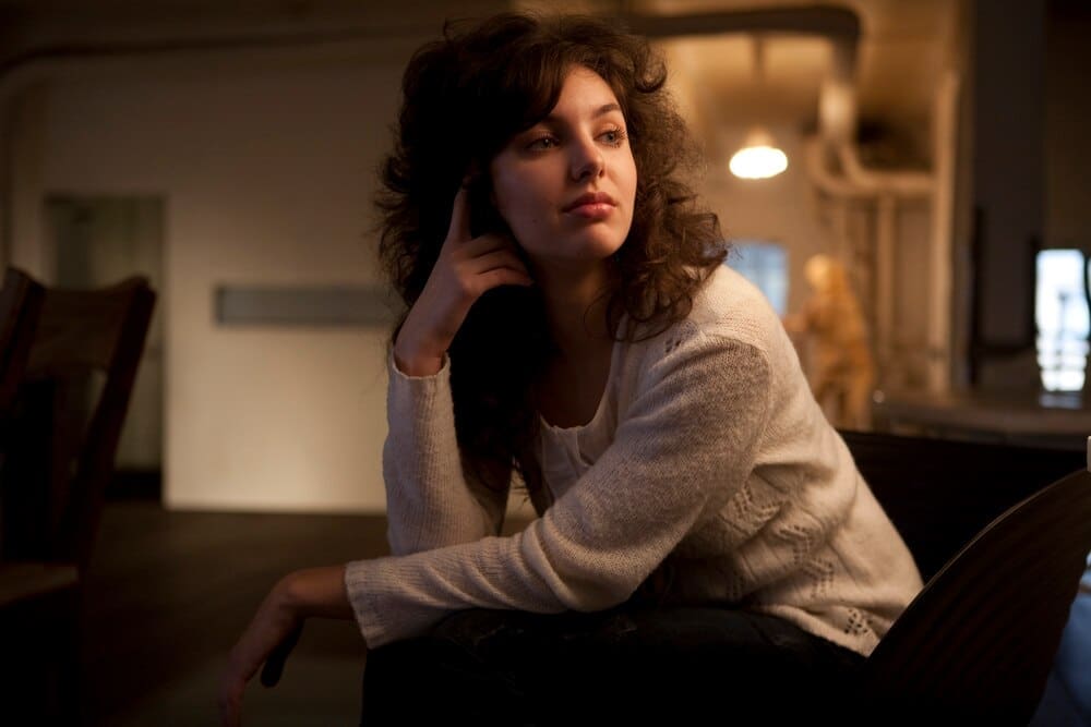 A woman with a gentle smile poses indoors.