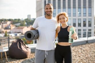 A young couple in athletic wear exercises outdoors in front of a city backdrop.