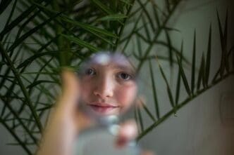 Young woman gazes at herself in a mirror.