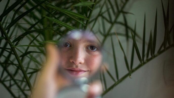 Young woman gazes at herself in a mirror.