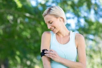 A blonde woman with her hair in a ponytail jogs on a path in a park.