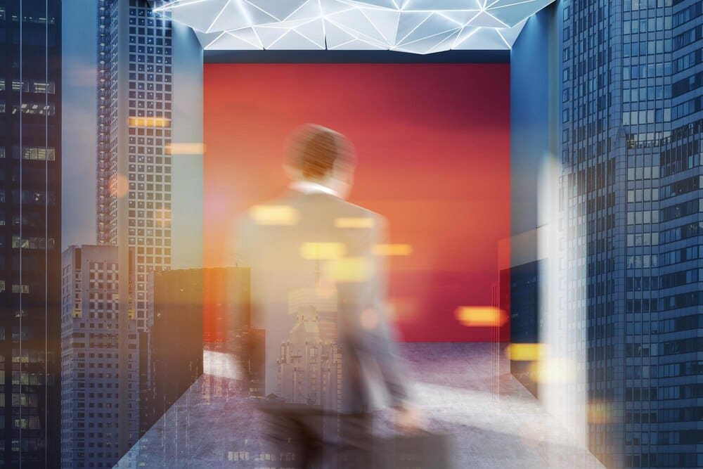 Rear view of a businessman walking down an empty hall with red walls and a geometric ceiling, overlaid with a toned double exposure effect.