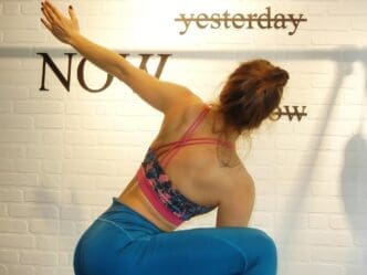 A woman in workout clothes stretches against a wall.