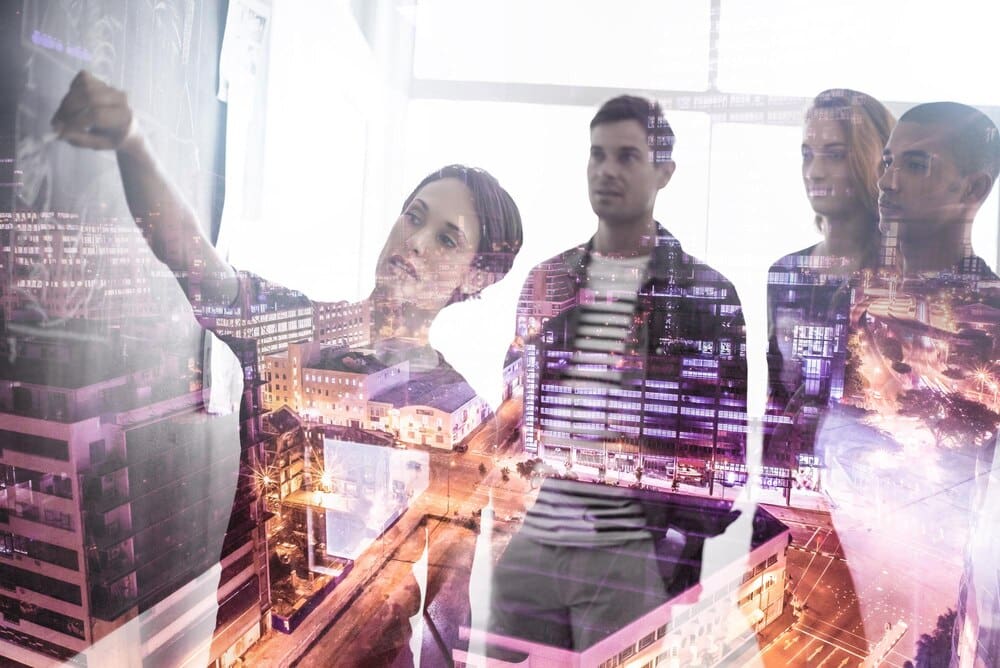 Multiple exposure image of businesspeople collaborating on city plans, overlaid on a cityscape.