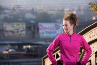 Woman in athletic wear stretches her legs and arms before a morning run.