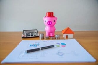 A hand places a coin into a piggy bank, illustrating the concept of saving money.