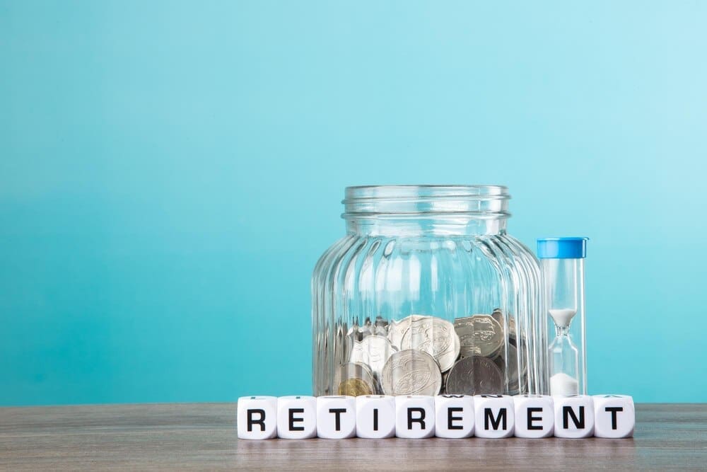 A person is putting coins into a piggy bank, symbolizing saving money for retirement.