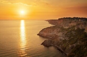 A scenic view of a rocky coastline at sunset.